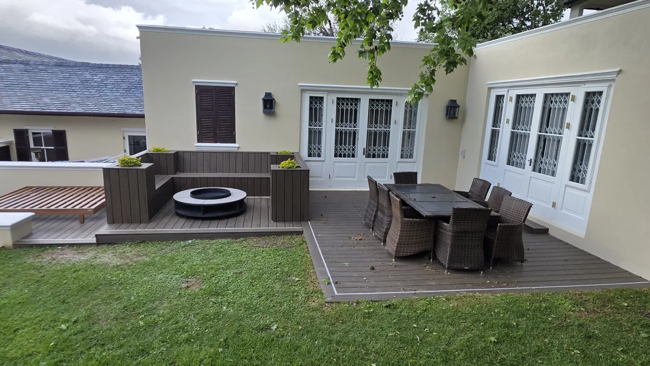 Composite deck wrapping a garden, with fire pit lounge and dining area