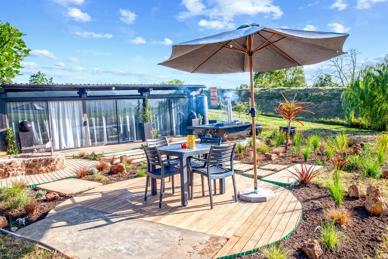 Garden suite — Outdoor table and umbrella on a circular timber deck in front of the suite