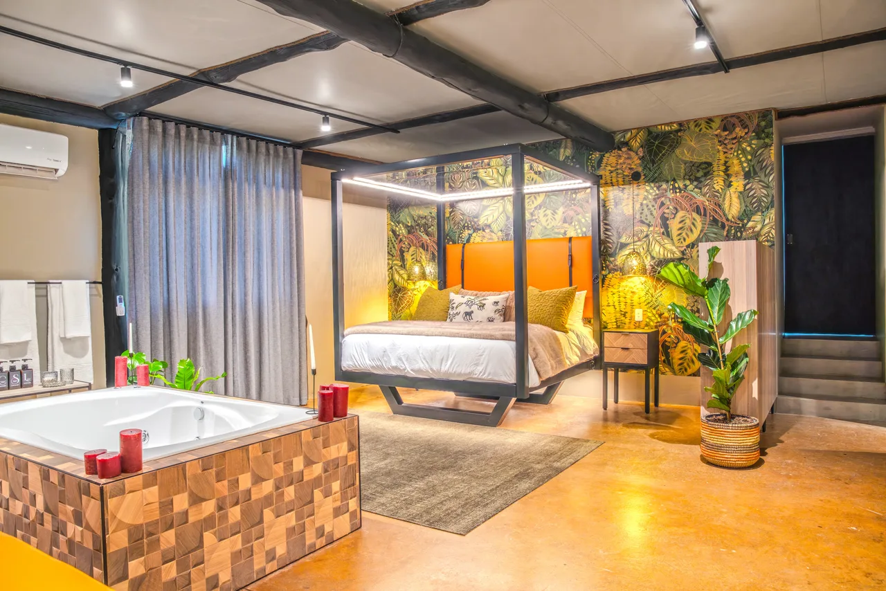 Garden suite — Suite interior with a four-poster bed, jungle wallpaper and a spa bath in the foreground