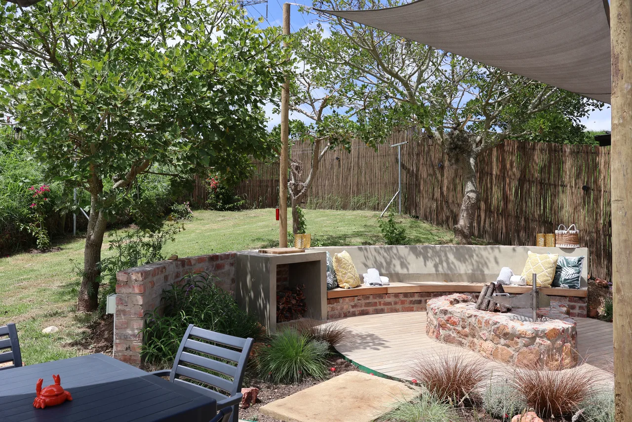 Garden suite — Stone fire pit and seating in the garden beside a shade sail