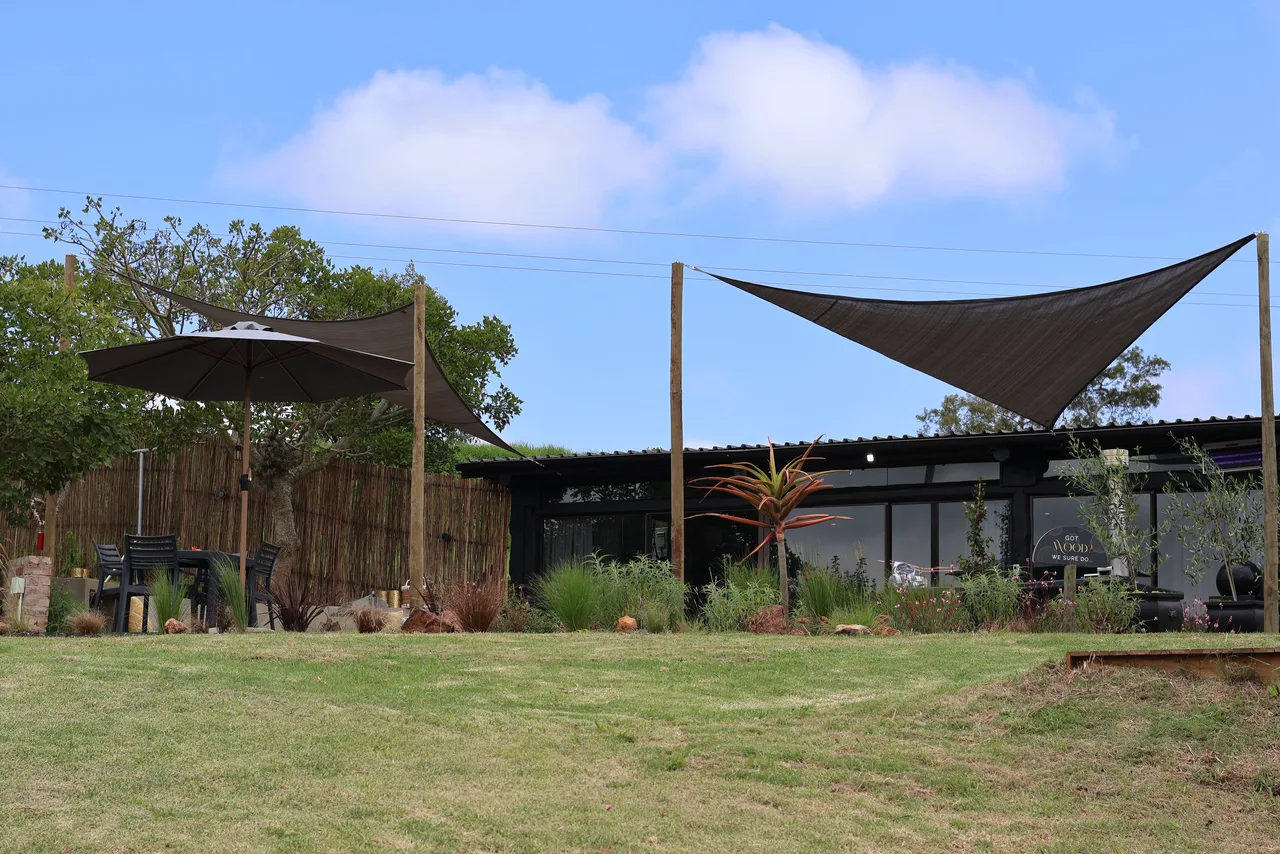 Garden suite — Shade sails and trees over the lawn beside the garden suite