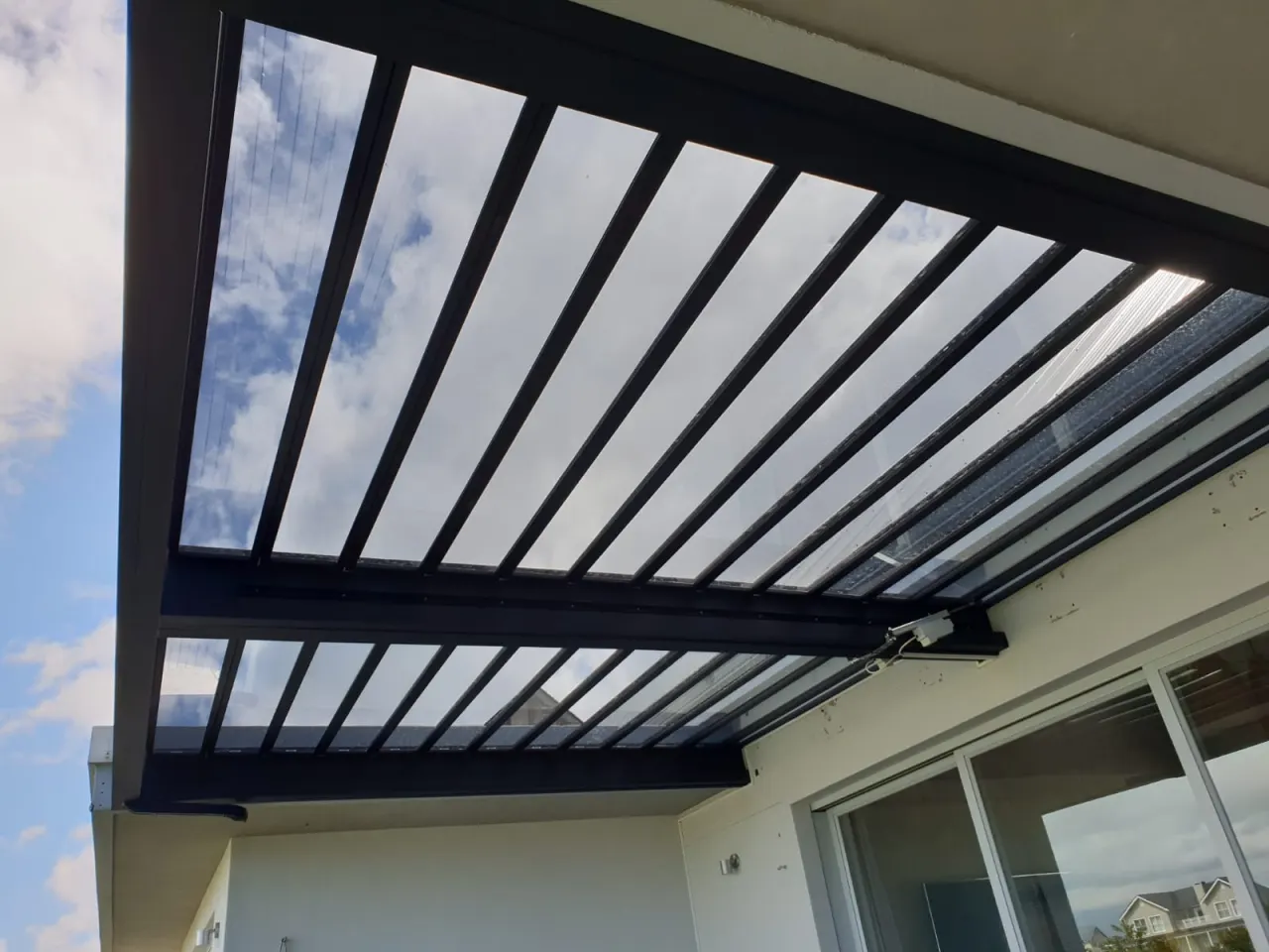 Charcoal louvre blades angled open against the sky