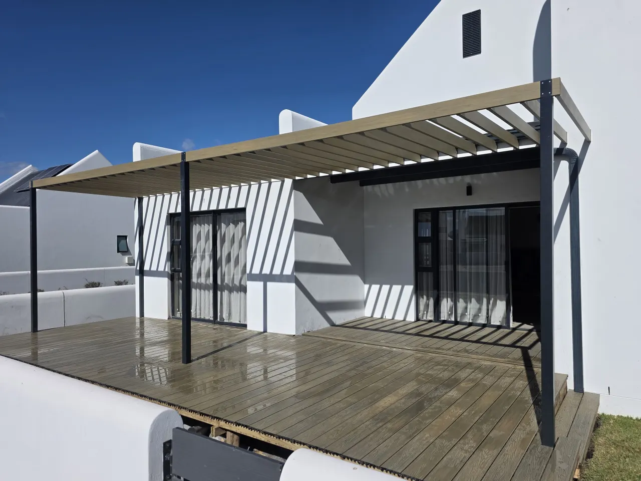 Pergola and deck along the length of a white house