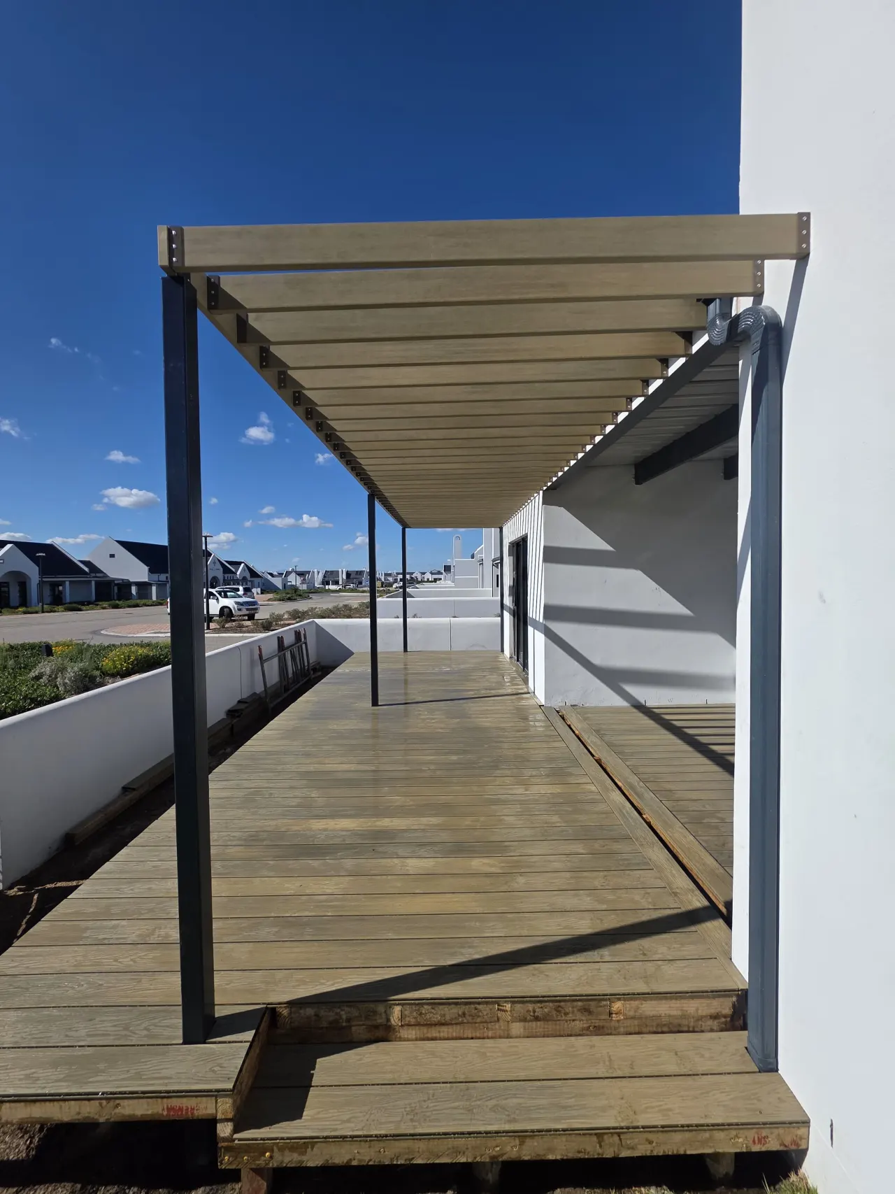 Long timber deck walkway under a slatted pergola