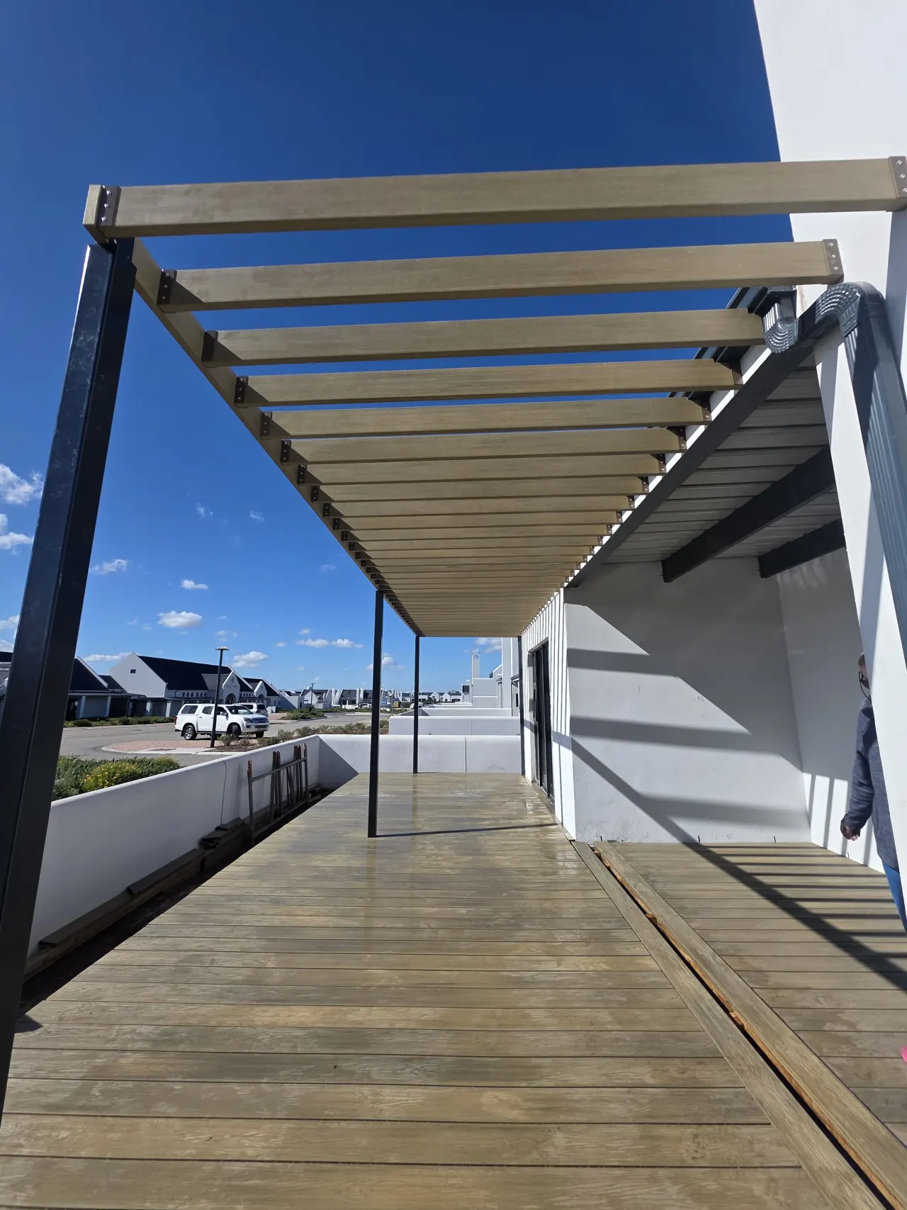 Looking along pergola slats against a blue sky