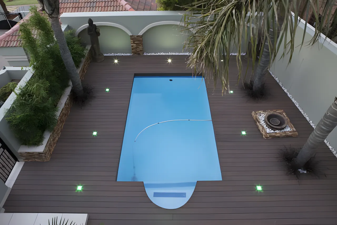 Dark composite deck with lit steps around a pool
