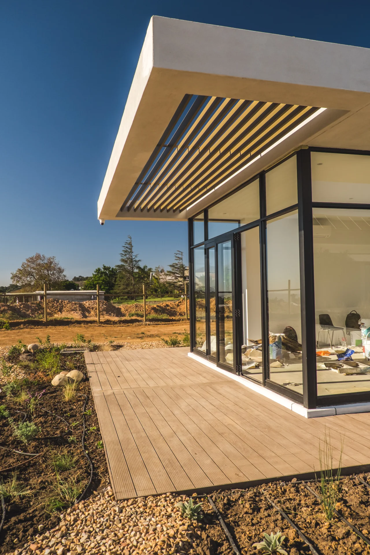 Slatted aluminium louvre canopy over a glass corner and timber deck at the Valdevie project