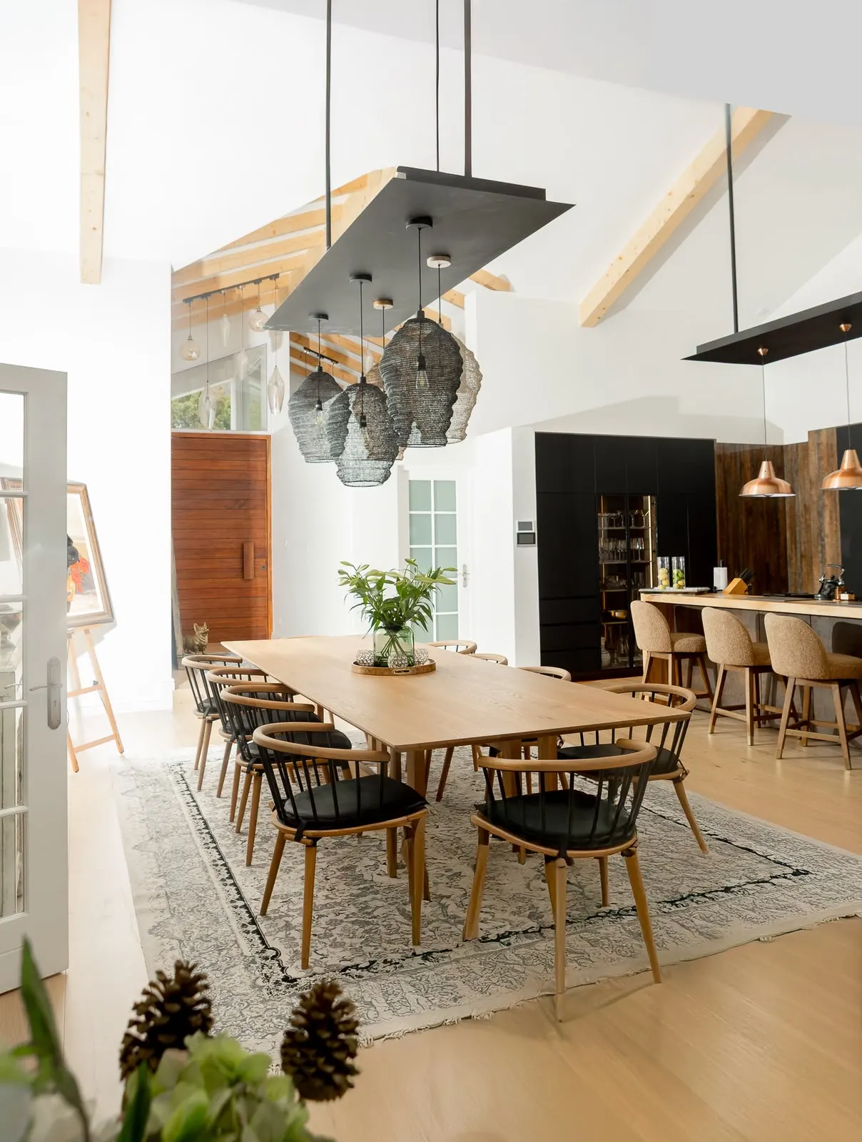 Dining table under woven pendants and exposed trusses