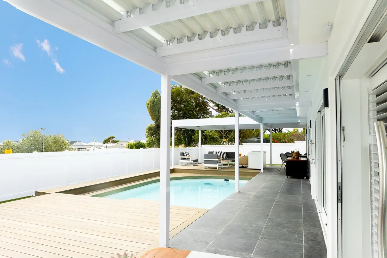 Covered walkway under a white pergola beside the pool
