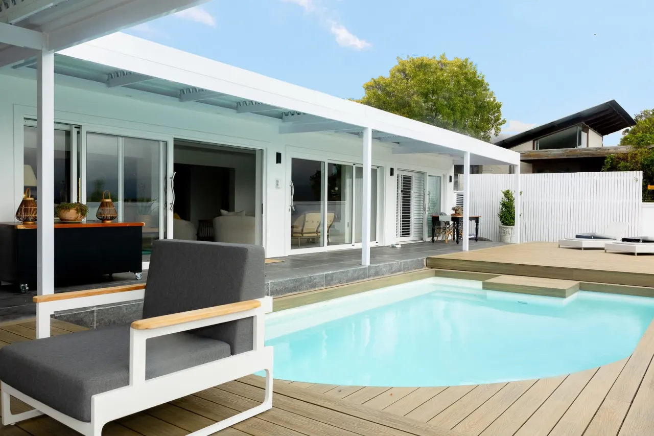 Pool and timber deck beside a white pergola at the Westlake house
