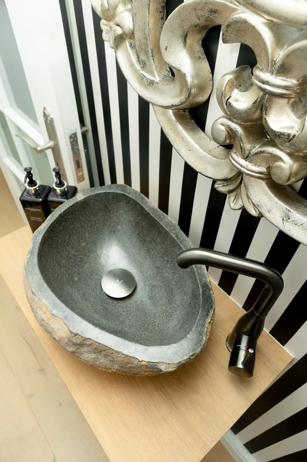 Stone vessel basin against striped wallpaper in the guest bathroom