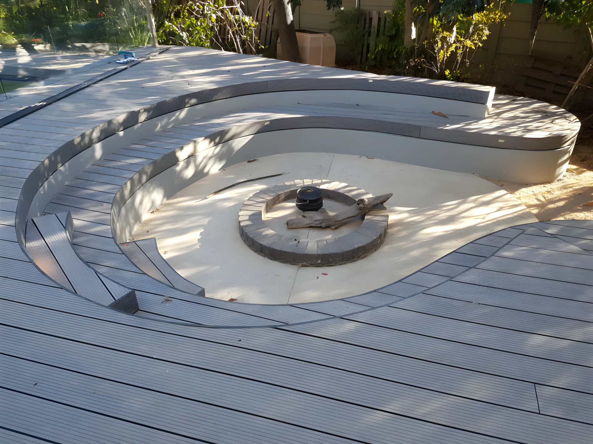 Curved tiered seating around a sunken fire pit set into composite decking