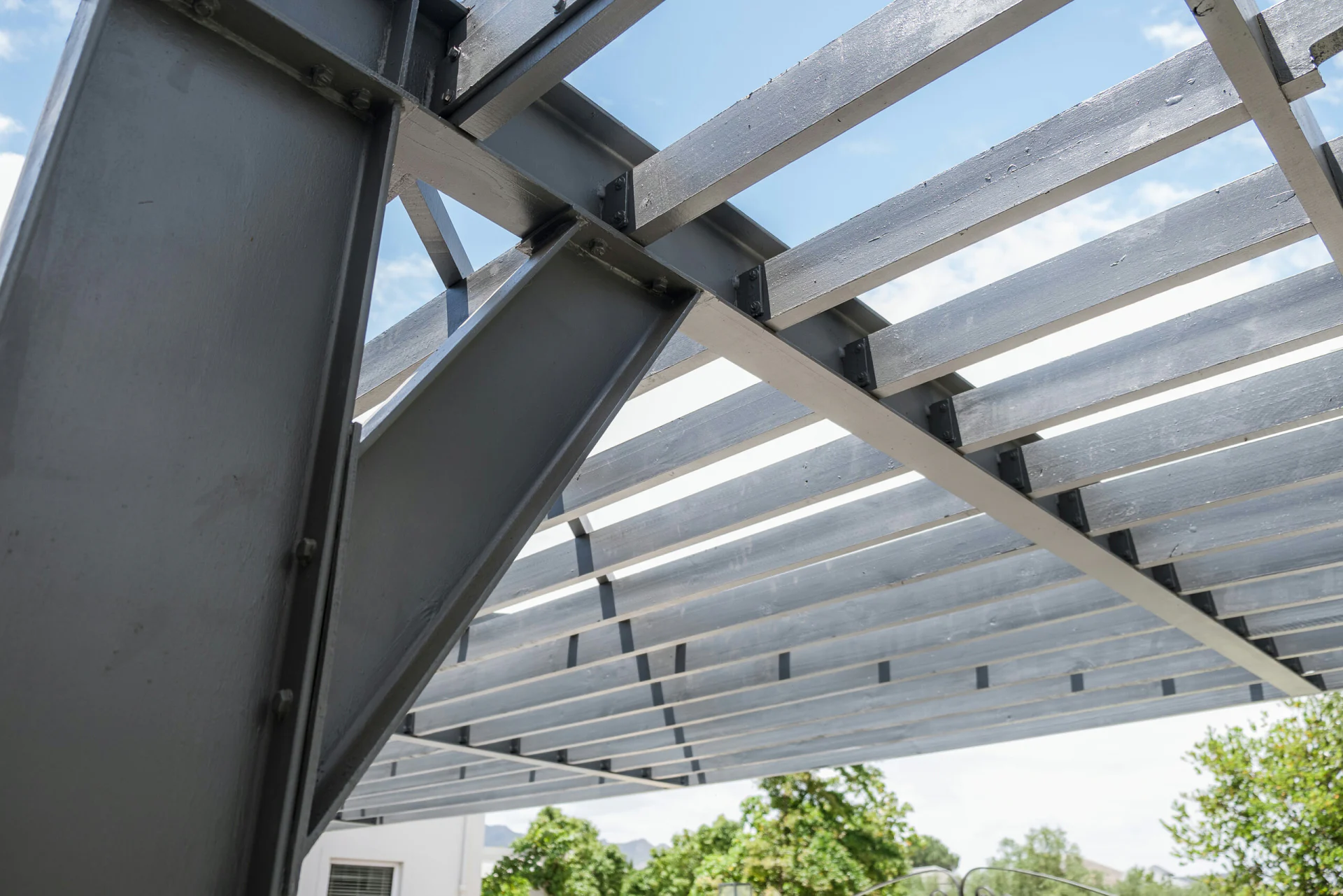 Looking up through charcoal steel pergola beams at the sky