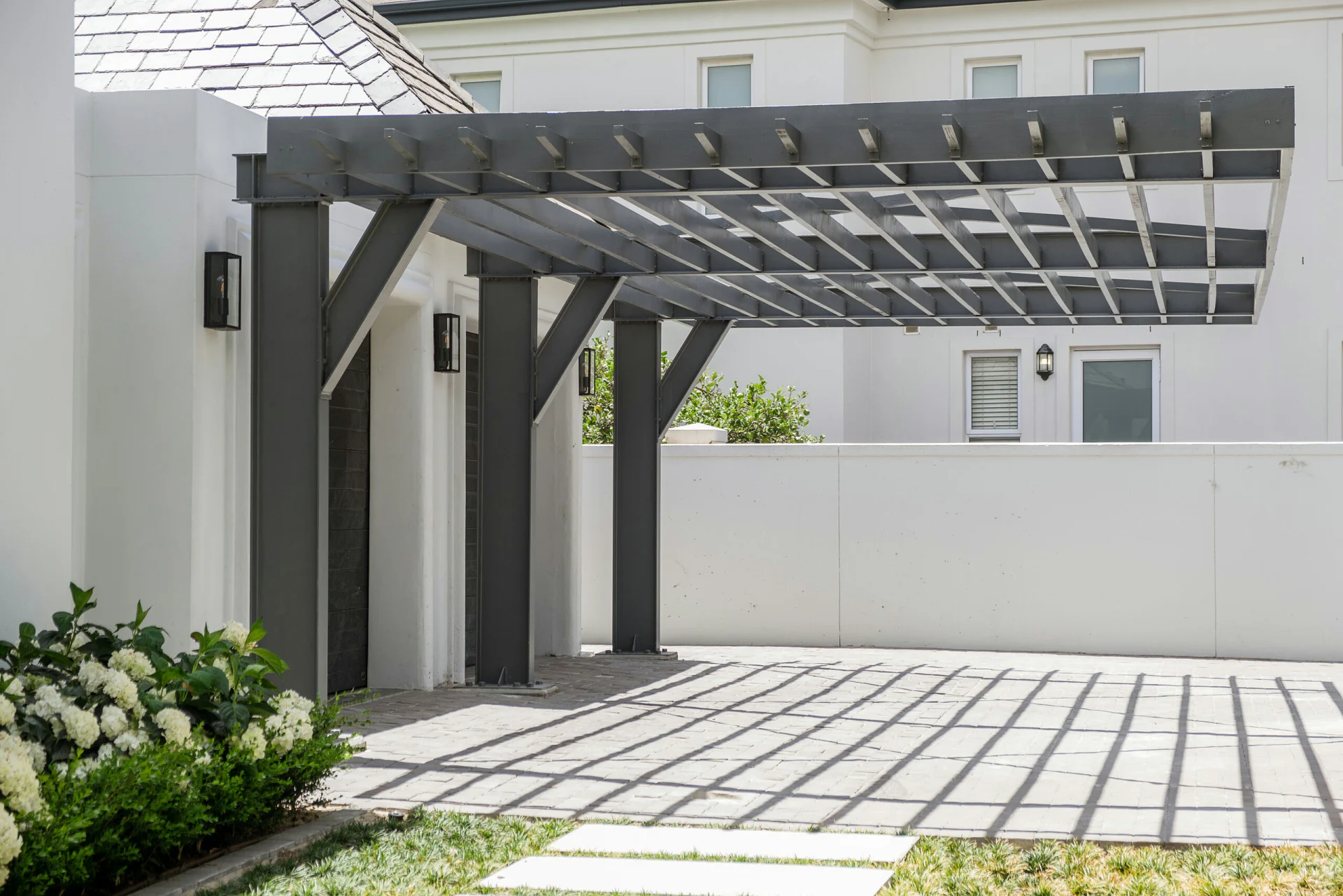 Charcoal steel pergola spanning a paved courtyard
