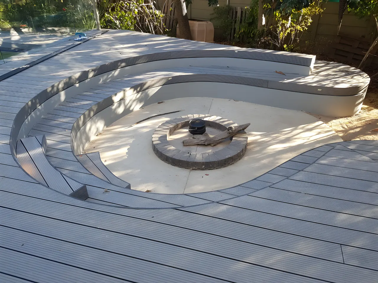 Curved tiered seating around a sunken fire pit set into composite decking