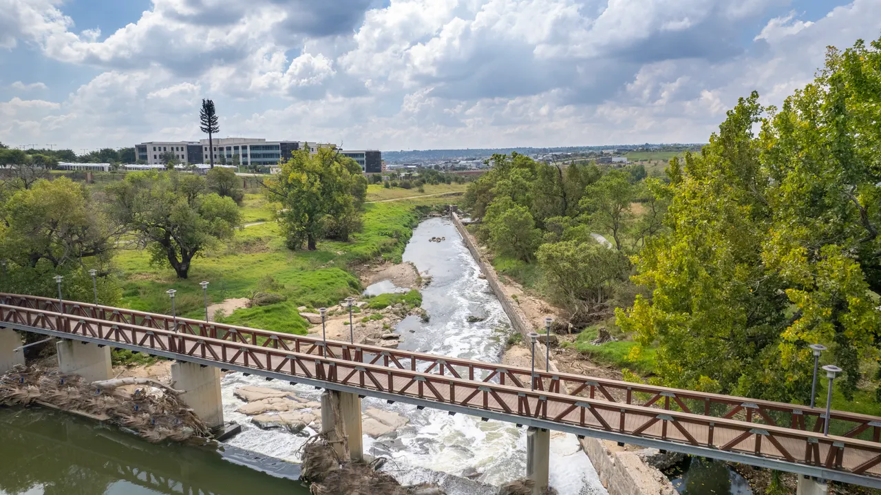 Red steel truss bridge spanning river rapids