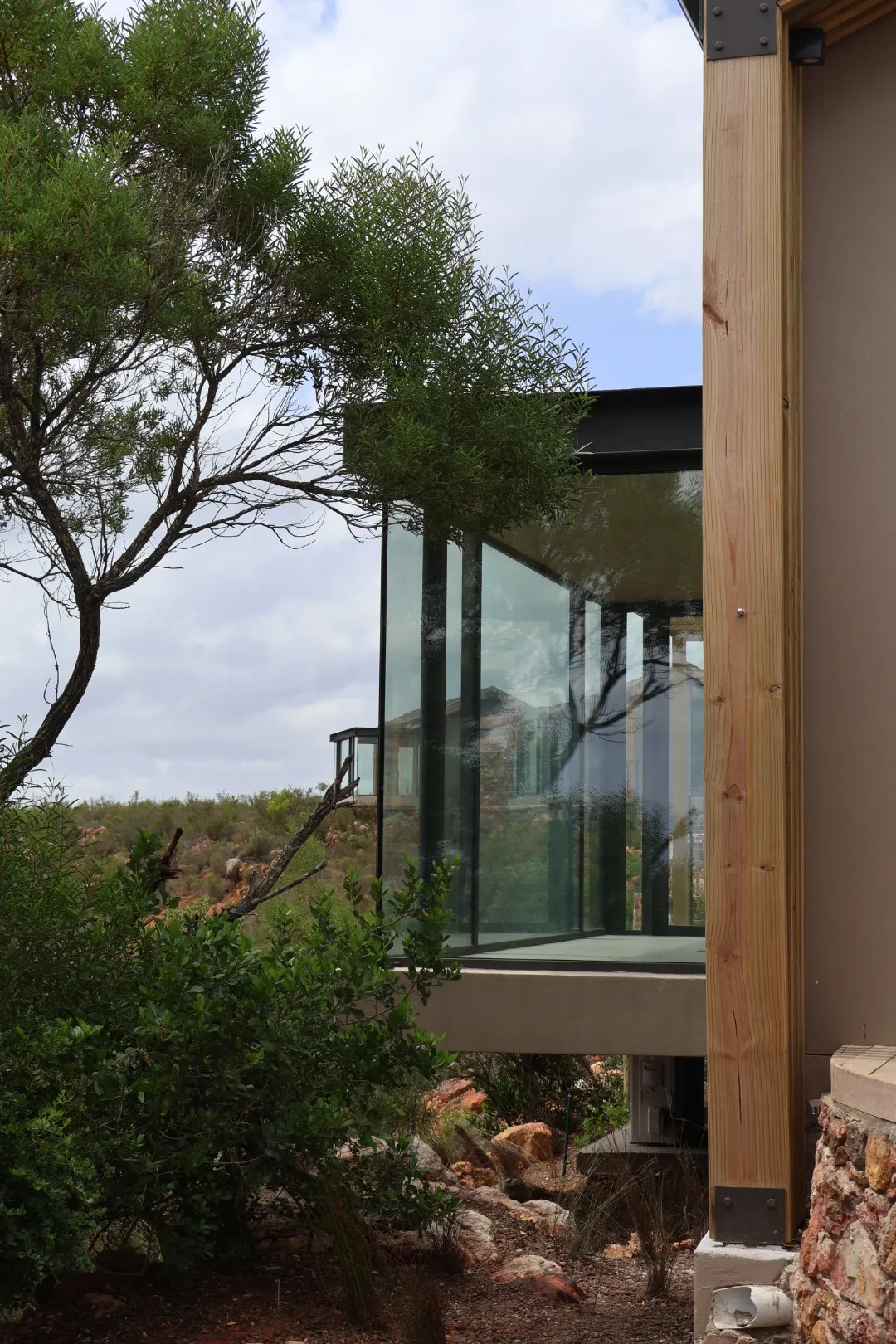 Frameless glass corner of a lodge suite looking over the fynbos