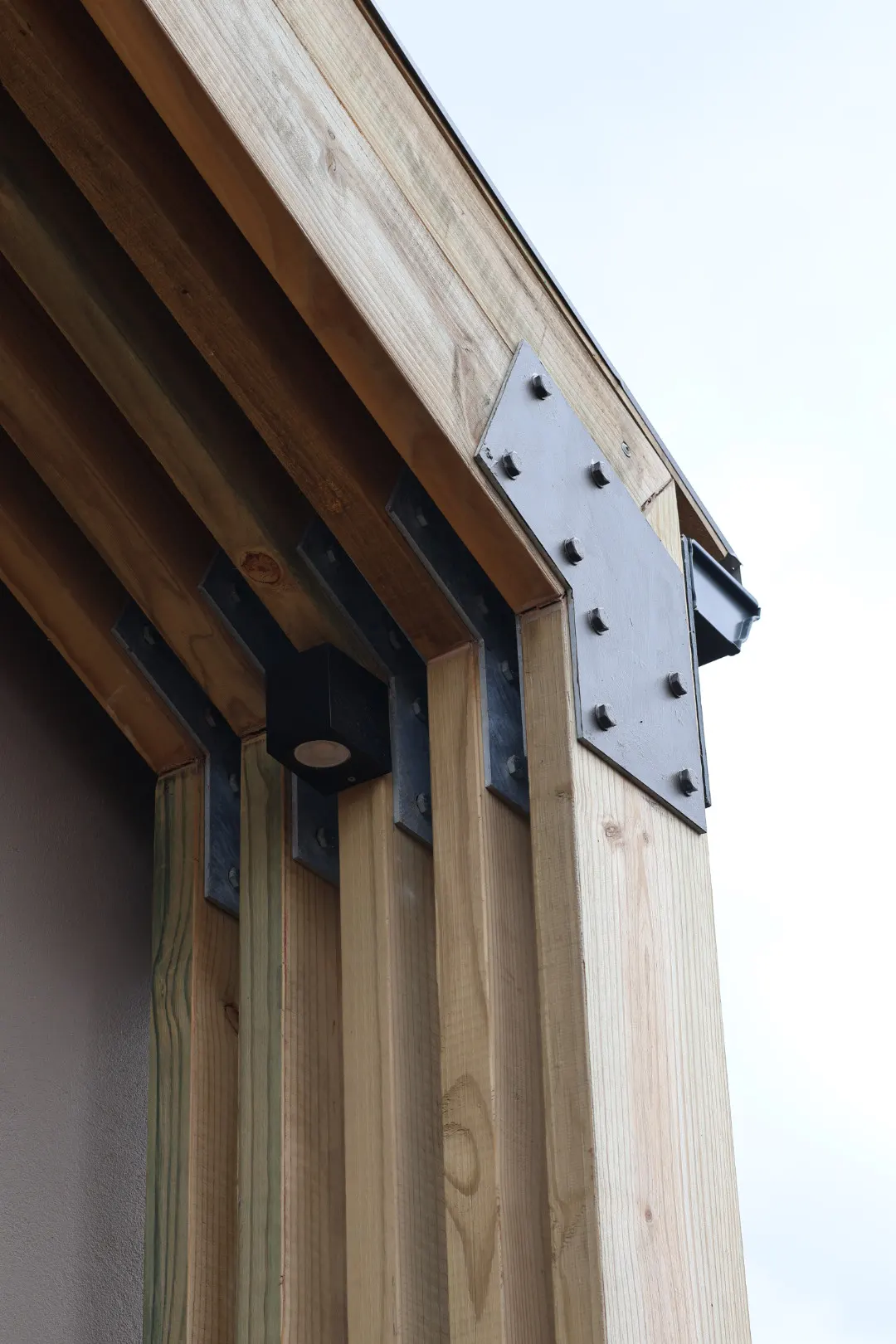 Bolted steel plate meeting timber cladding
