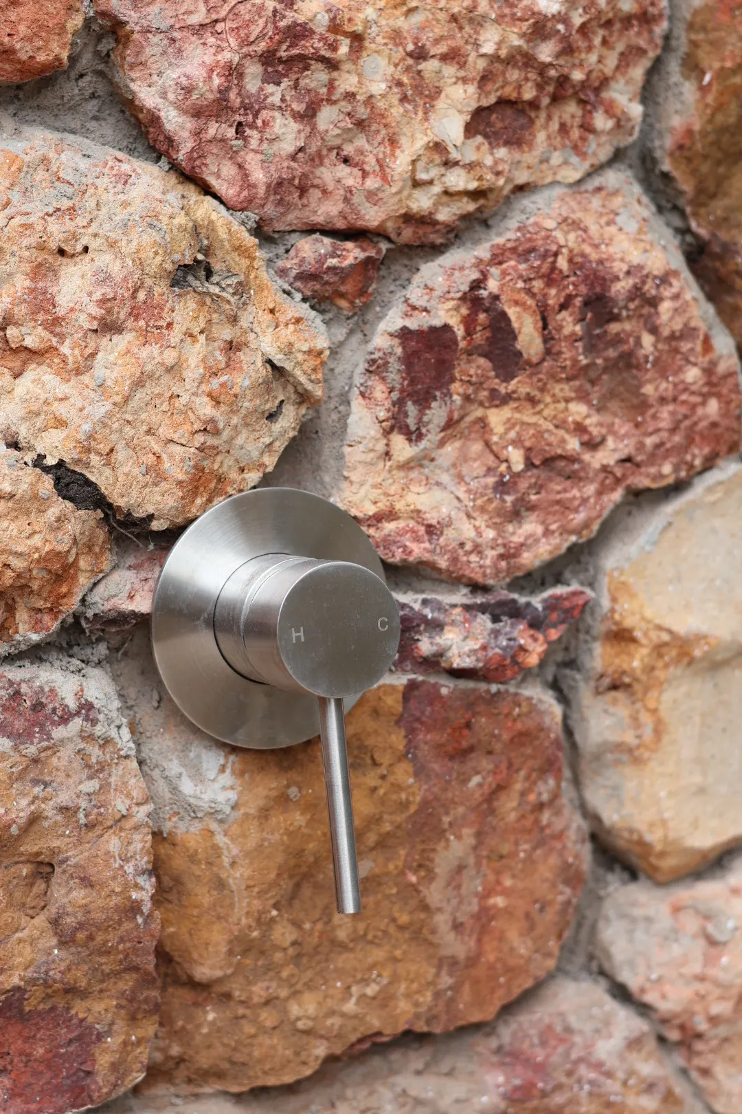 Brushed steel mixer set into a hand-laid stone wall