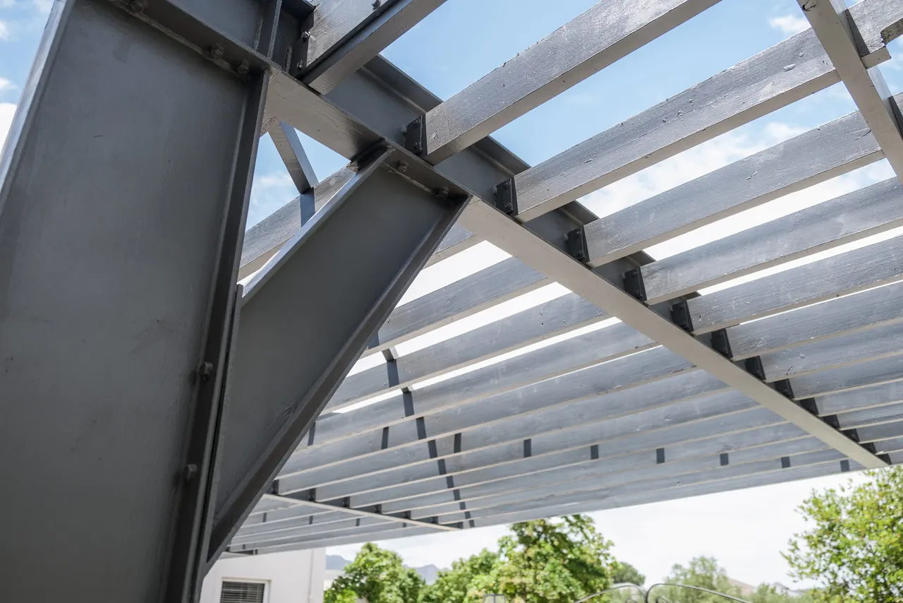 Looking up through charcoal steel pergola beams at the sky