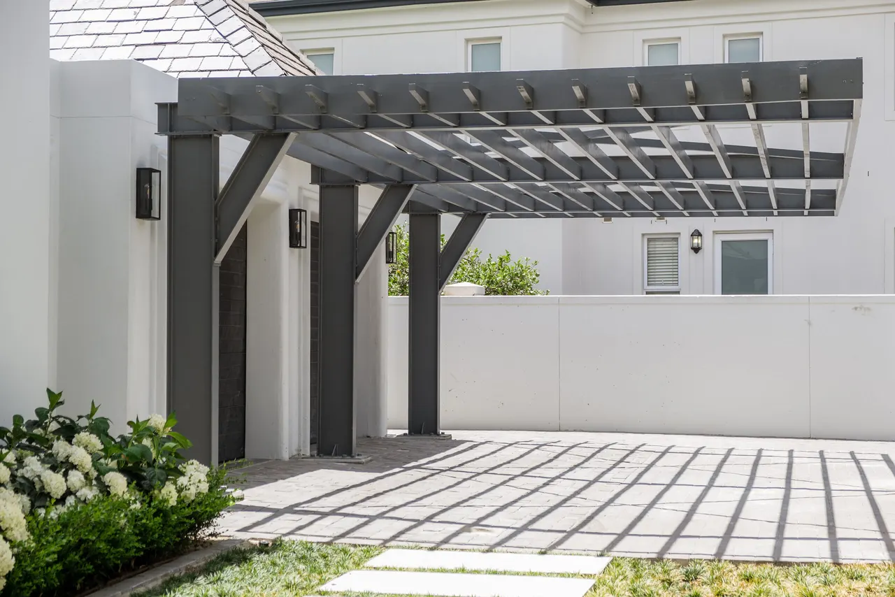 Charcoal steel pergola spanning a paved courtyard